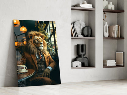 Glass wall art leaning against white wall displays a lion wearing brown suit seated at café table with orange pendant lights above.