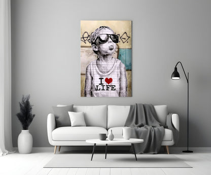 Glass wall art depicting a child wearing sunglasses and "I Love Life" shirt displayed above a white sofa in a modern living room.