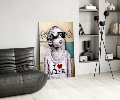 Glass wall art leaning against white wall displays sketch-style child wearing sunglasses with "I ❤ LIFE" text on shirt.