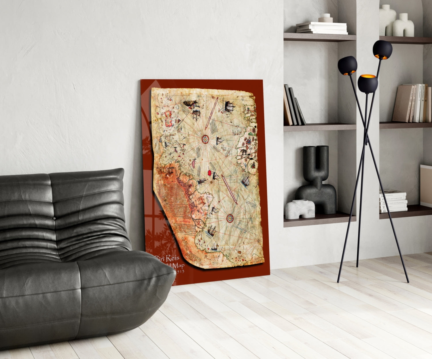 Modern living room interior featuring a Piri Reis Map artwork with red border and antique parchment design leaning against white wall next to black leather chair.