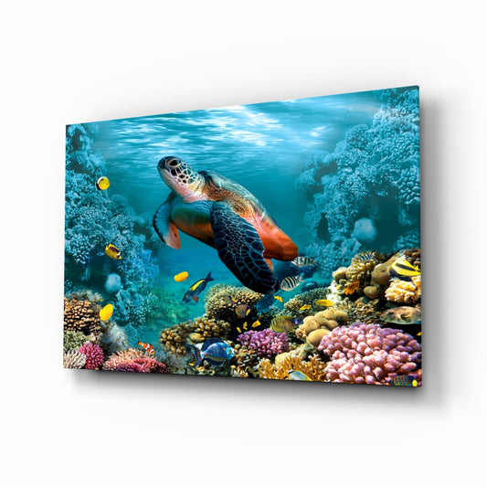 Glass wall art panel displaying an underwater coral reef scene with a sea turtle, tropical fish, and colorful corals in vibrant blues and oranges.