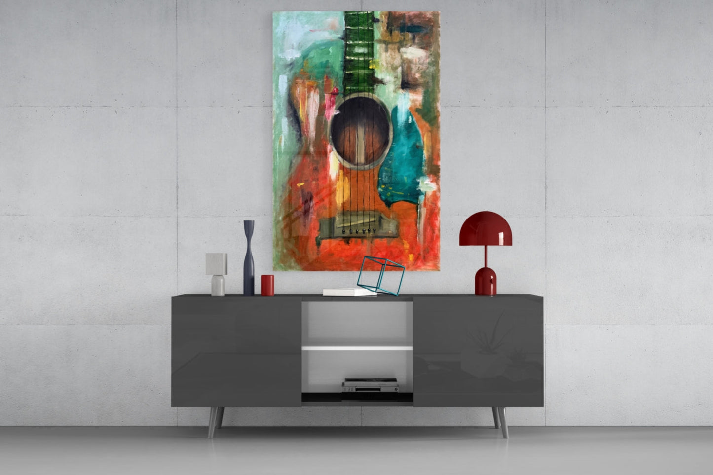 Colorful abstract guitar glass wall art displayed above a dark gray media console with decorative accessories in a modern interior setting.