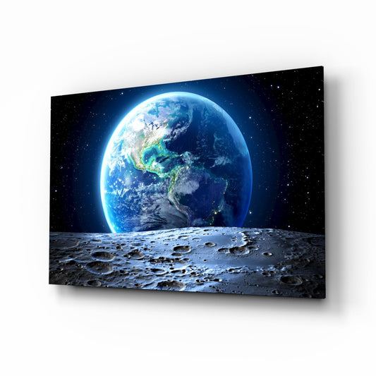Earth rising above a cratered lunar surface against a starlit black sky, displayed as angled glass wall art.