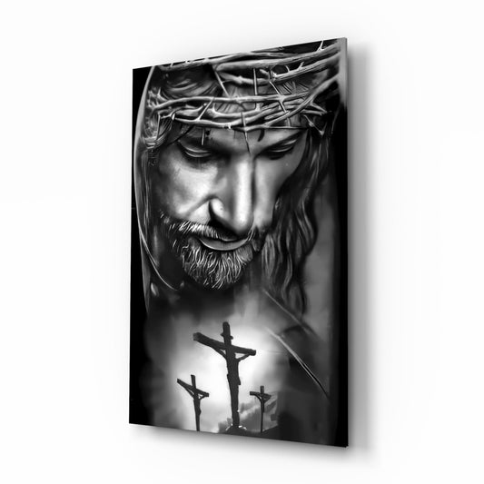 Black and white glass wall art displaying a sculptural Jesus head with crown of thorns above three silhouetted crosses, angled three-quarter view.