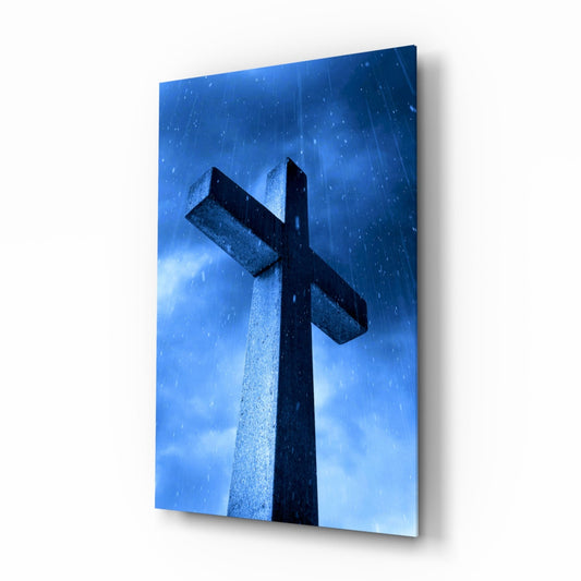 Stone cross silhouetted against dramatic blue sky with rain, viewed from below at an upward angle.