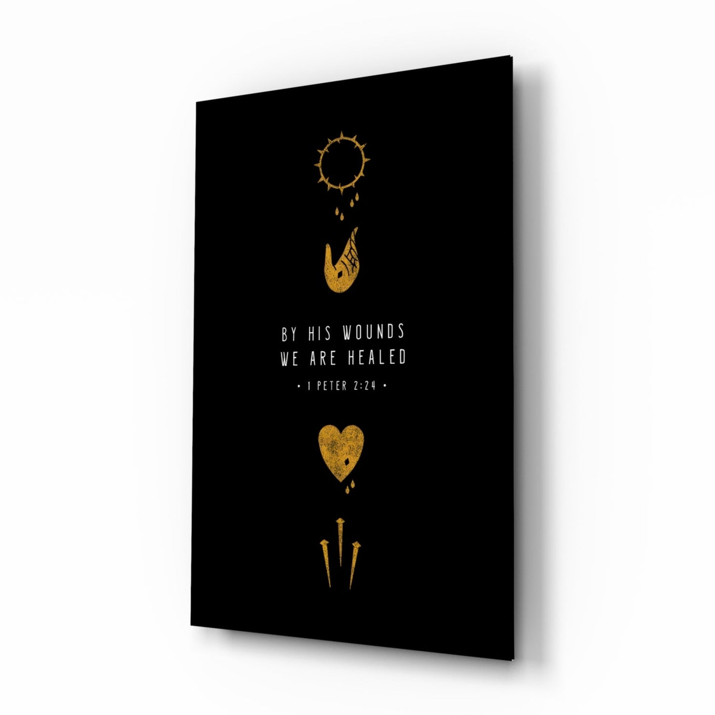 Black glass wall art panel with gold religious symbols and white text reading "By His Wounds We Are Healed - 1 Peter 2:24," displayed at an angle.
