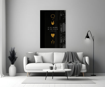 Black glass wall art with gold religious symbols and "By His Wounds We Are Healed" text displayed above white sofa in modern living room.