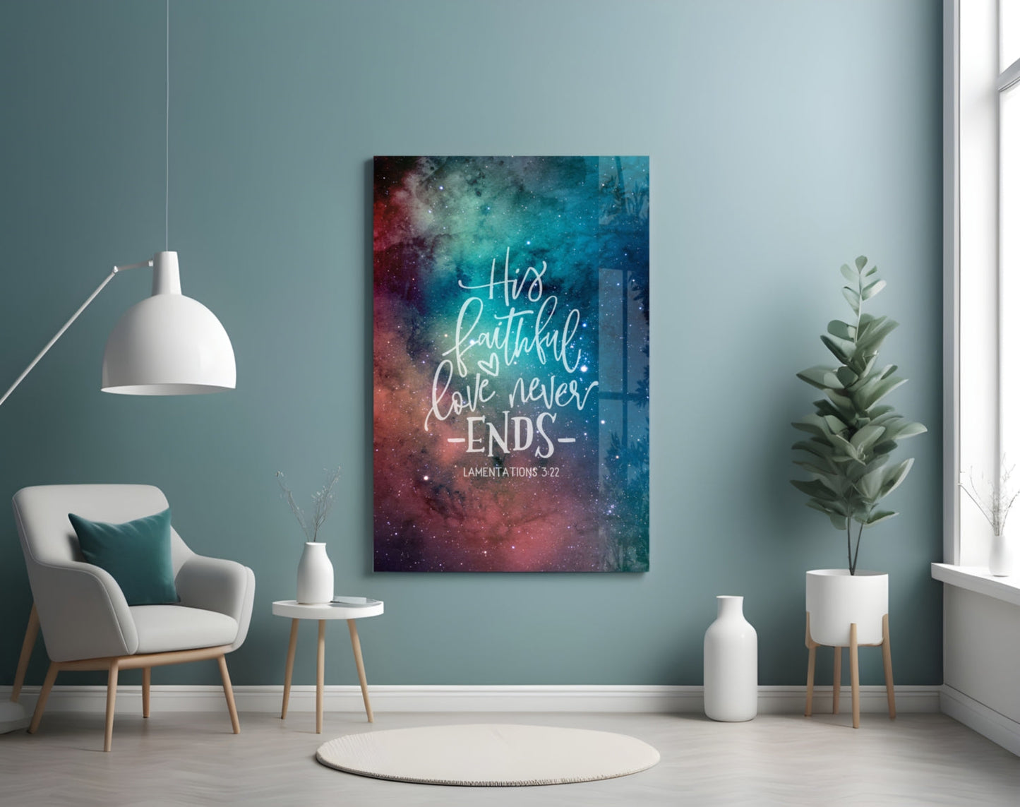 Glass wall art with galaxy background and white handwritten text "His faithful love never ends - Lamentations 3:22" displayed in modern room setting.