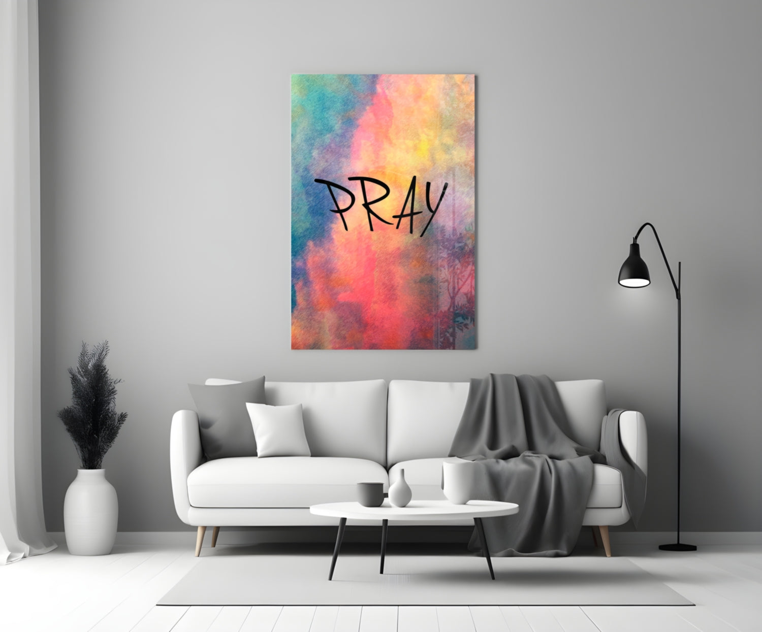 Colorful watercolor glass wall art displaying "PRAY" text in black lettering, hung above a white sofa in a modern living room interior.