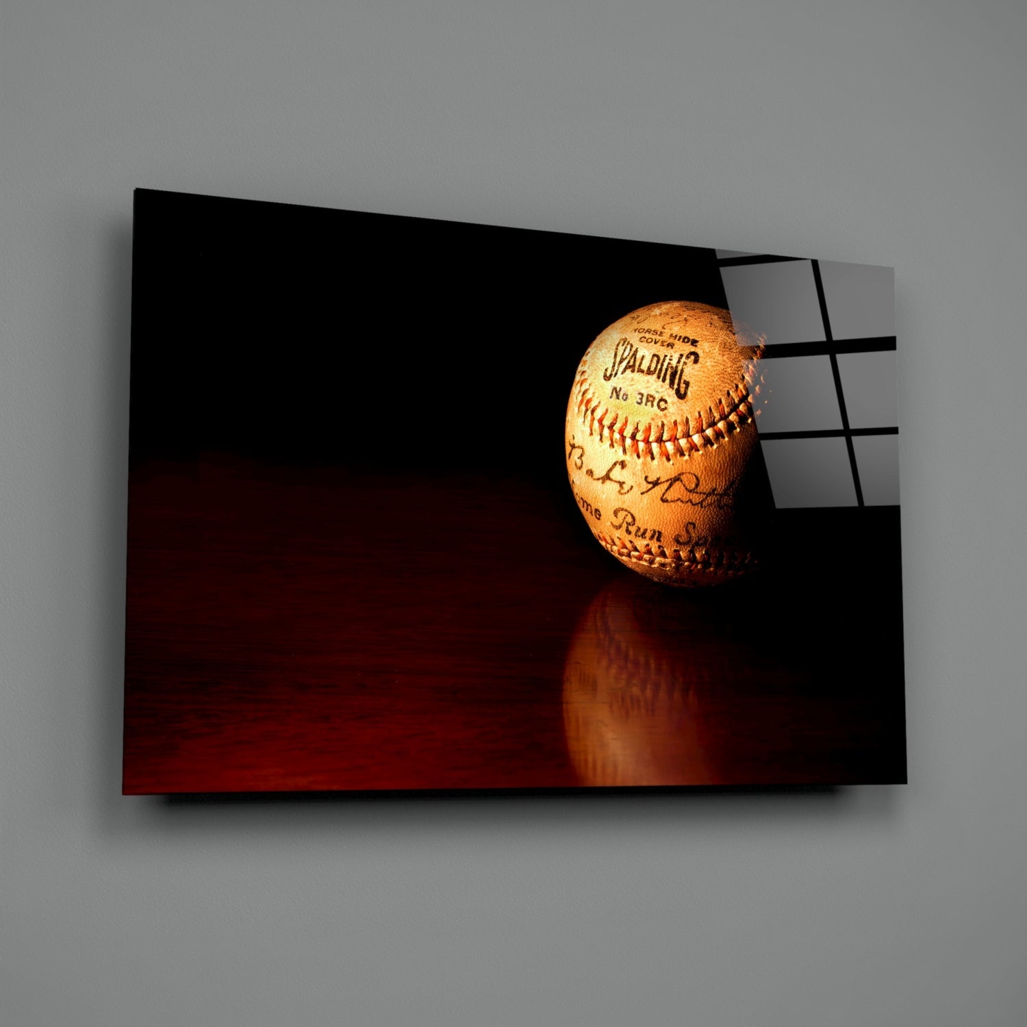 Spalding baseball displayed on glass wall art with dark red and black background, showing ball's stitching and signatures.