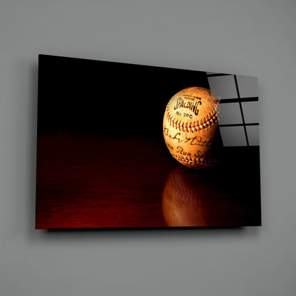 Spalding baseball displayed on glass wall art with dark red and black background, showing ball's stitching and signatures.