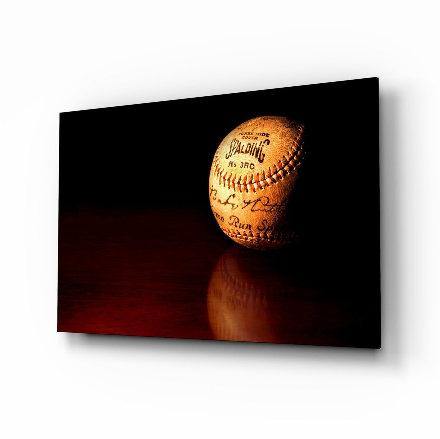 Vintage Spalding baseball with red stitching displayed on dark reflective surface against black background.