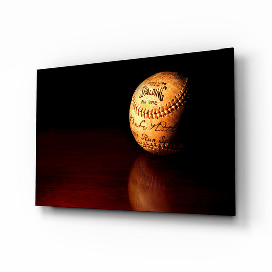 Vintage Spalding baseball with red stitching displayed on dark reflective surface against black background.