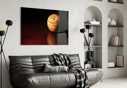 Baseball glass wall art displaying a vintage Spalding ball with red stitching mounted above a gray leather sofa in a modern living room.