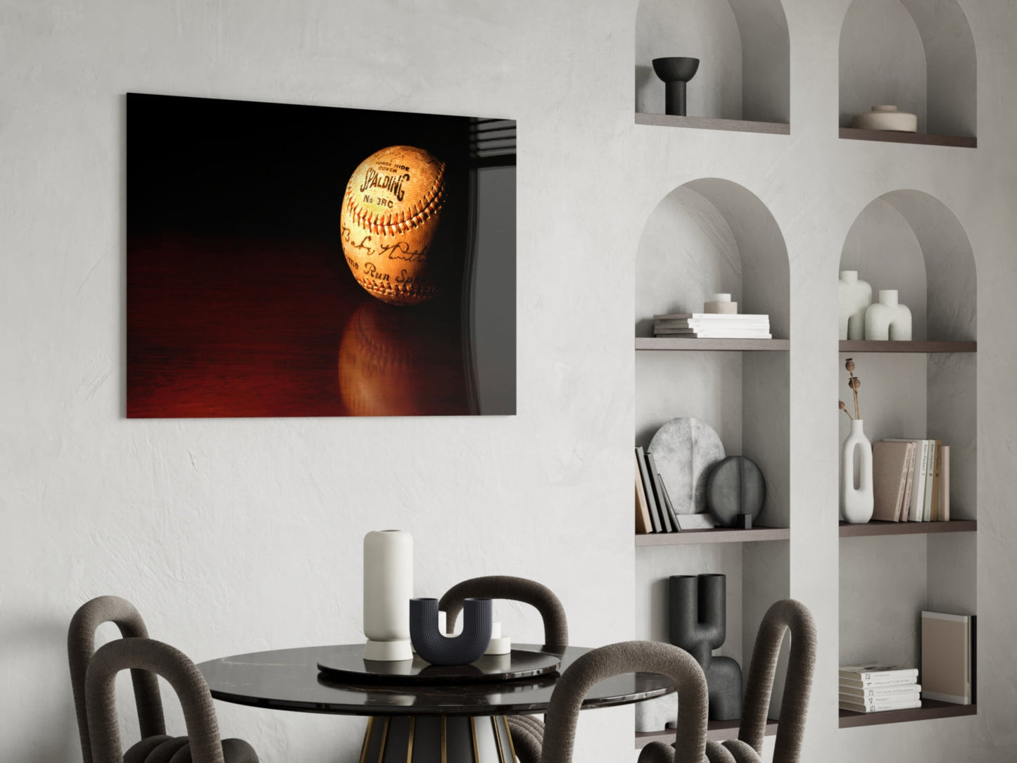Signed baseball with red stitching illuminated against dark red background, displayed above round black dining table in modern room setting.