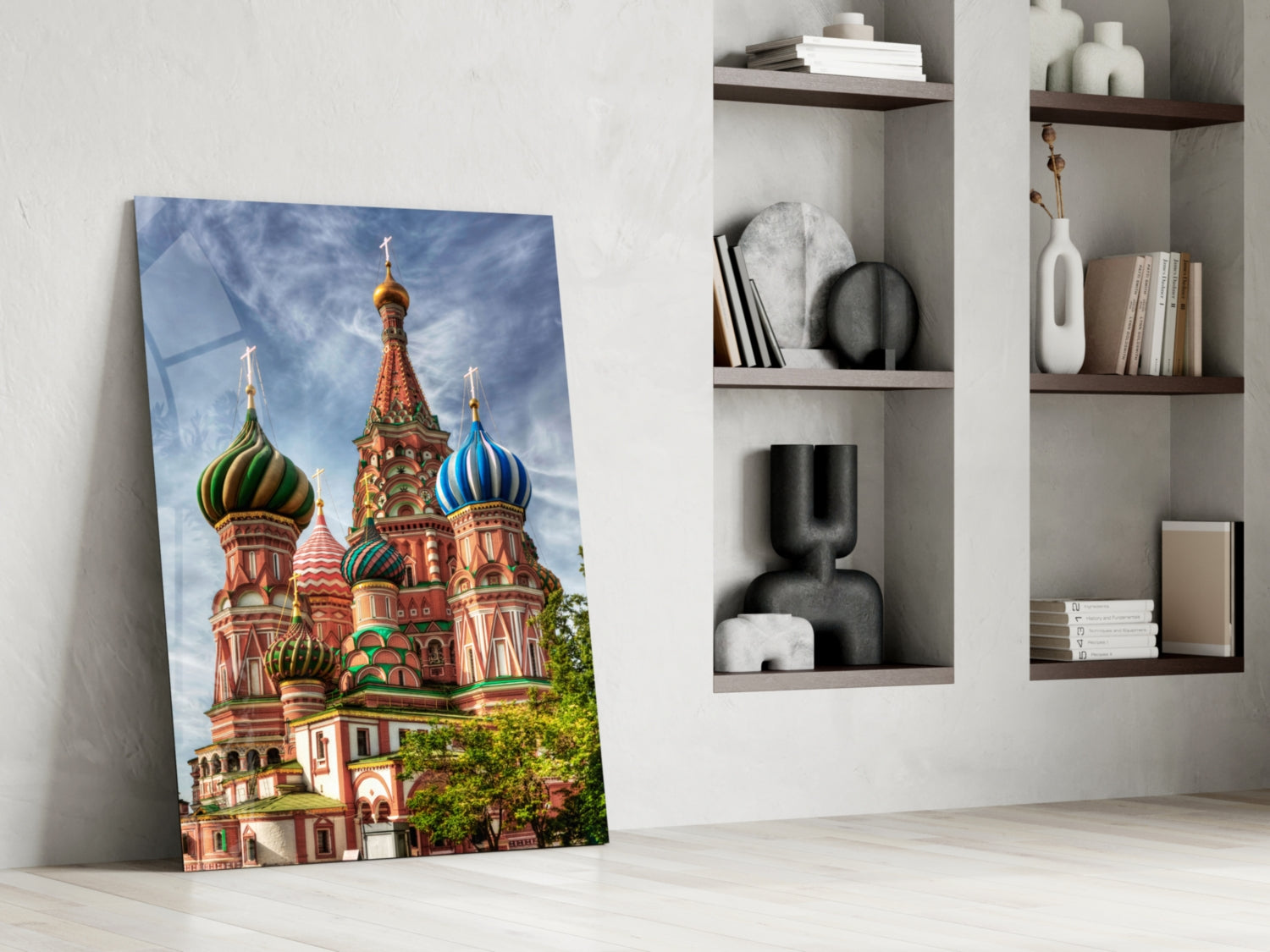 Glass art print of Saint Basil's Cathedral with colorful onion domes leaning against white wall beside shelving.