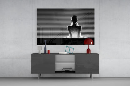 Black and white glass wall art featuring a seated figure with horizontal lines, displayed above a gray media console with red decorative accents.
