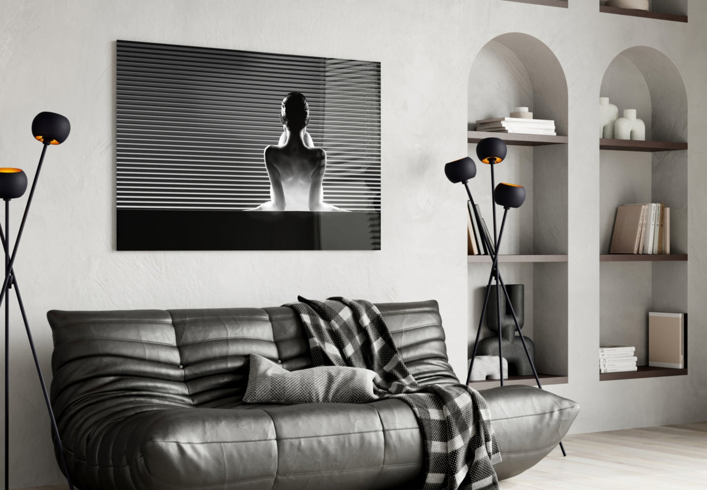 Black and white glass wall art depicting a silhouetted figure against horizontal lines, displayed above a black leather sofa in a modern living room.
