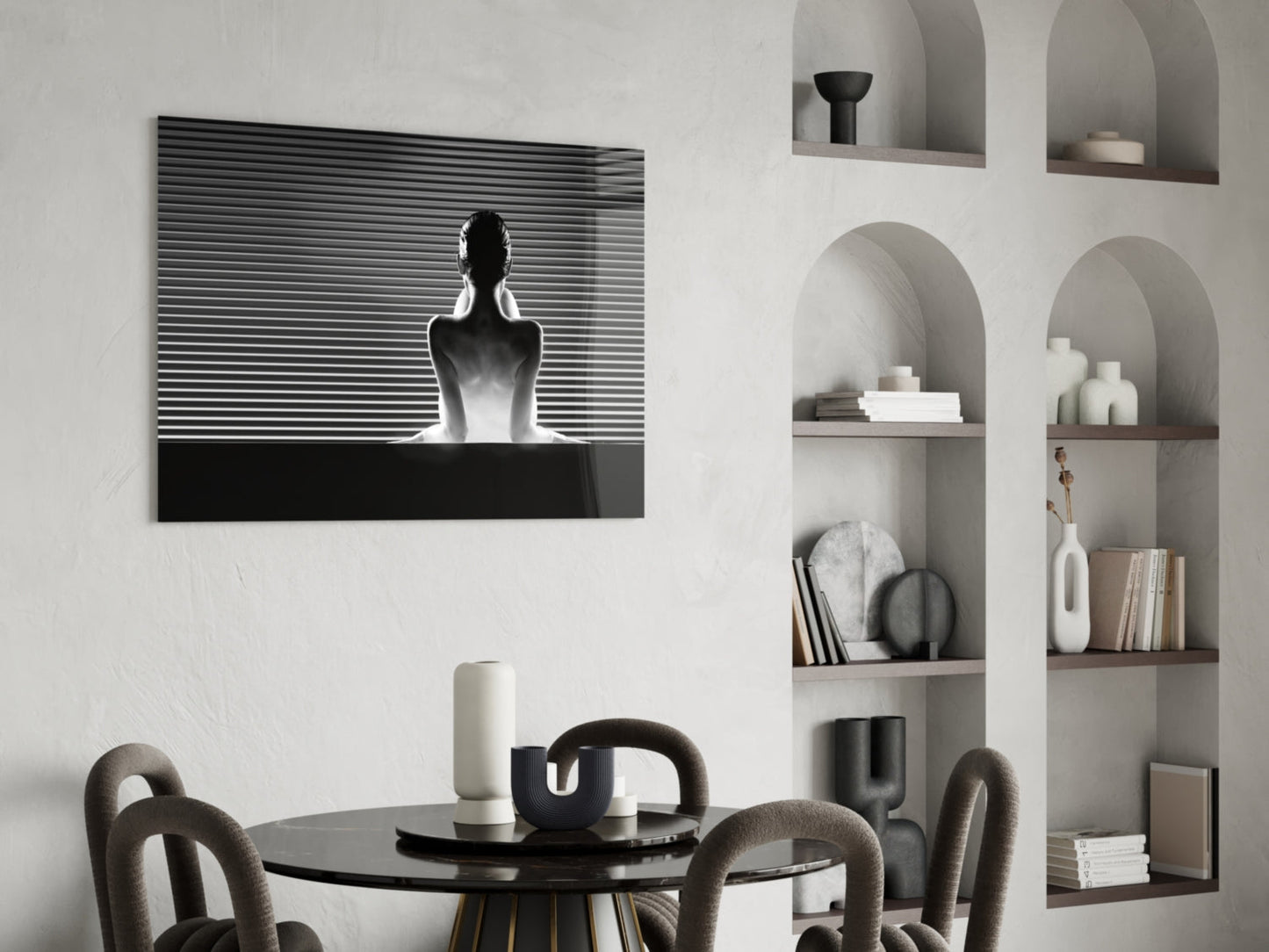 Black and white glass wall art depicting a silhouetted figure against horizontal lines, displayed above a dining table in a minimalist interior.