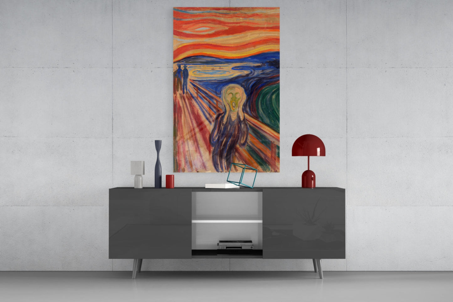 The Scream glass wall art displayed above a dark gray media console in a minimalist interior setting, showing the iconic expressionist painting with swirling orange, blue, and red tones.