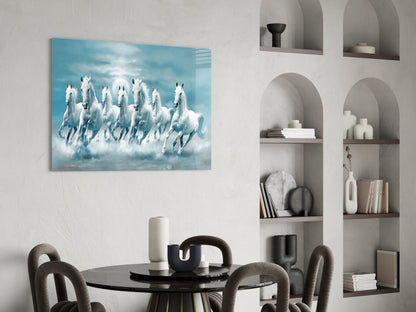 White horses galloping through clouds on blue glass art panel displayed above round black dining table.