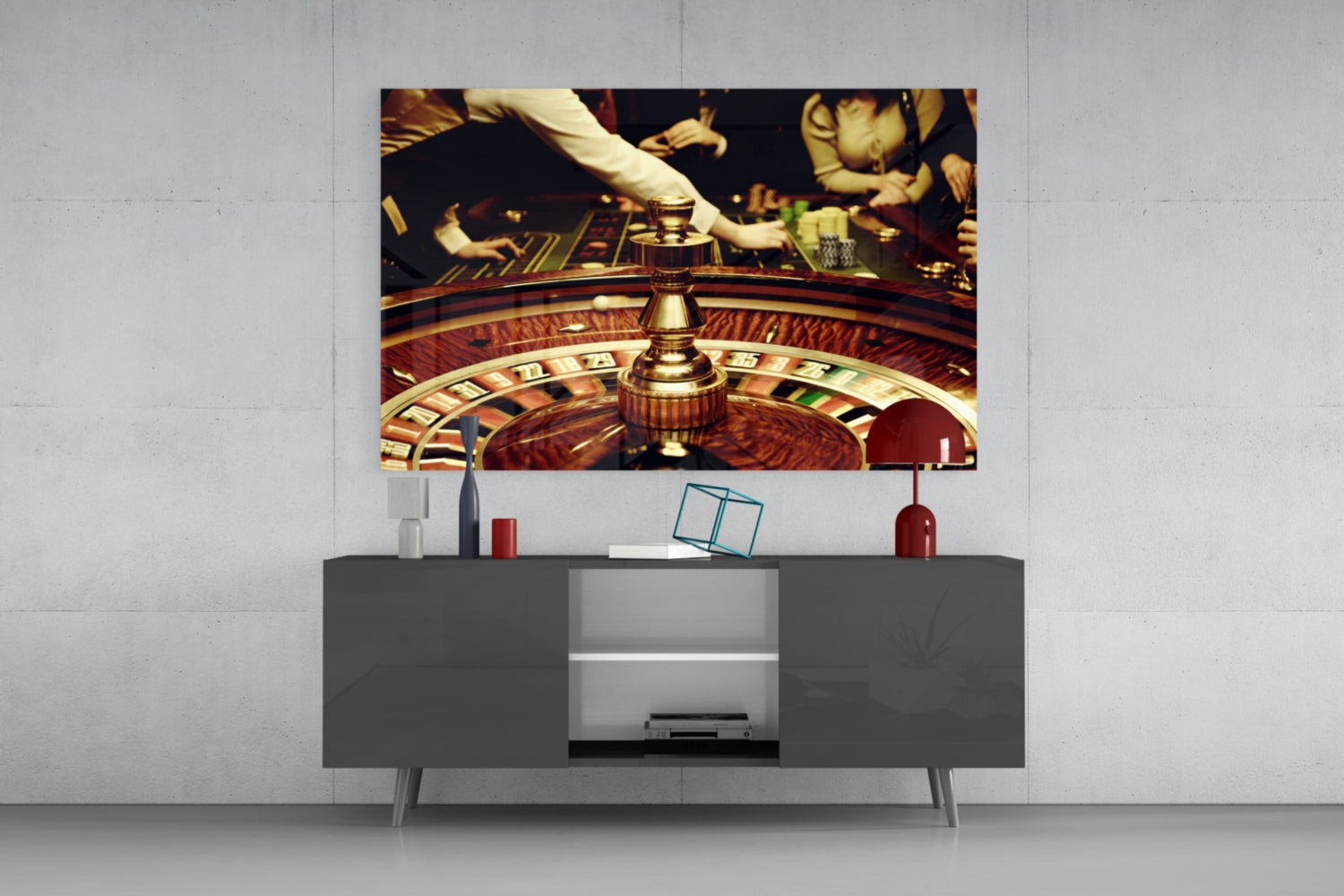 Glass wall art depicting a roulette wheel with casino players and chips mounted above a gray media console in a modern interior setting.