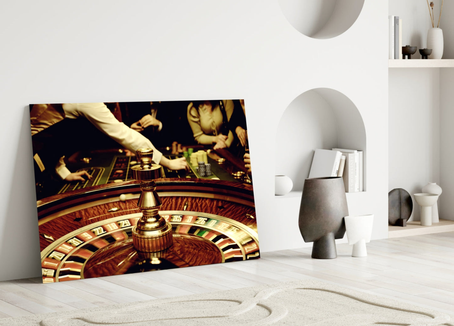 Gamble Glass Wall Art leaning against white wall in minimalist room, showing roulette wheel and casino scene in warm gold and brown tones.