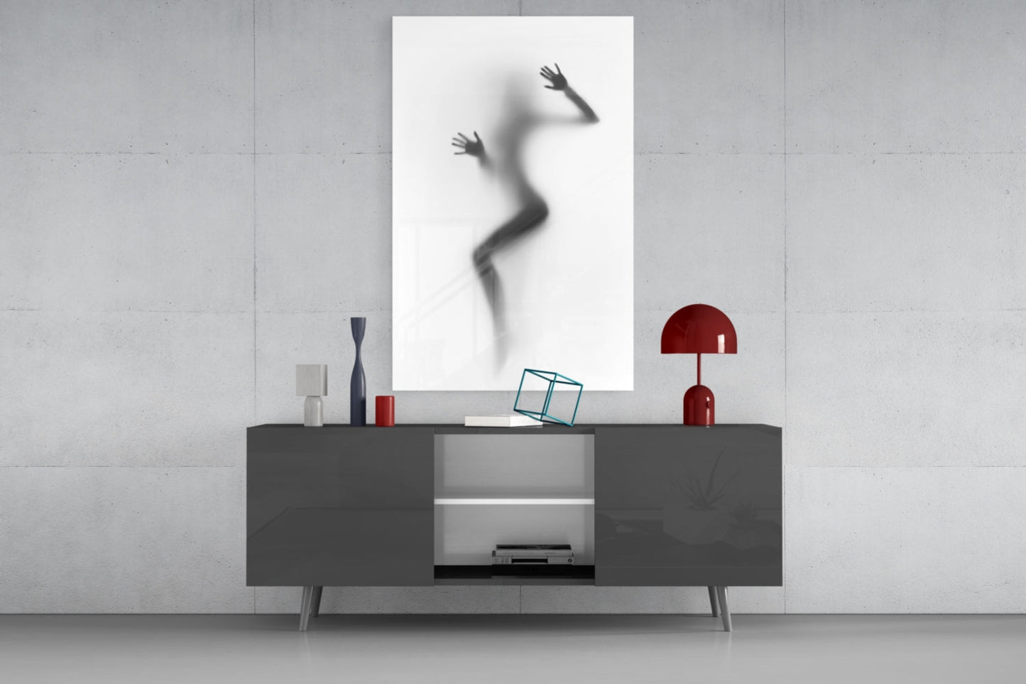 Modern living room display featuring a blurred silhouette of a woman in motion on a white framed glass panel mounted above a dark gray media console with red decorative accessories.