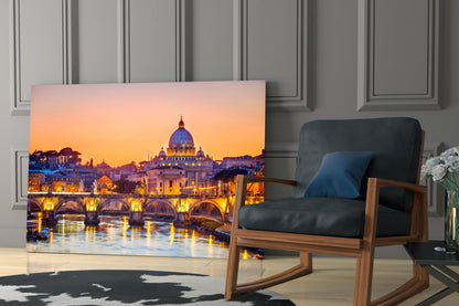 Glass wall art displaying St. Peter's Basilica at sunset with illuminated bridge and golden sky, displayed in modern living room setting.