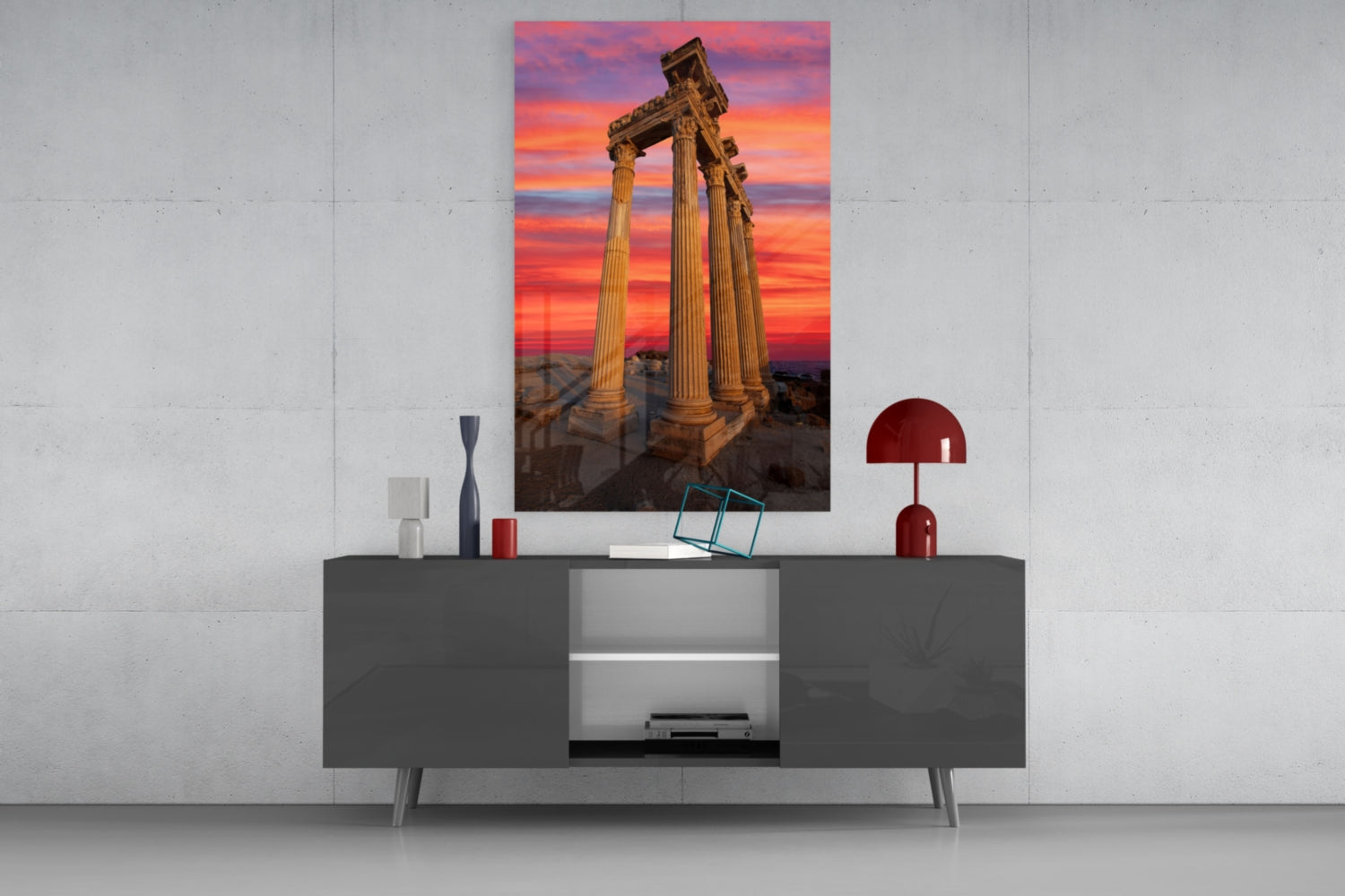 Temple of Apollo glass wall art displayed above dark gray media console, showing ancient columns against vibrant sunset sky.