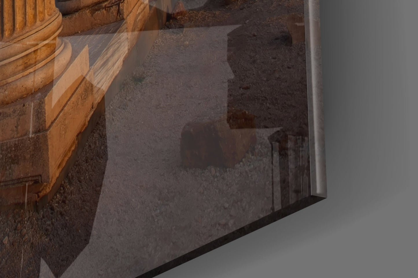 Close-up angled view of glass wall art showing carved wooden architectural details and stone surface with metallic frame edge.