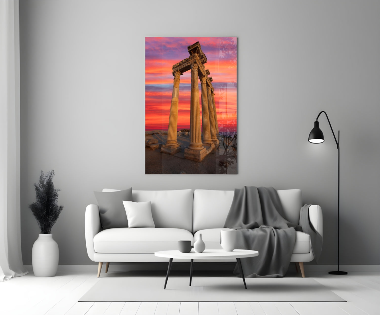 Temple of Apollo glass wall art displayed above a white sofa, showing ancient columns against a vibrant sunset sky.