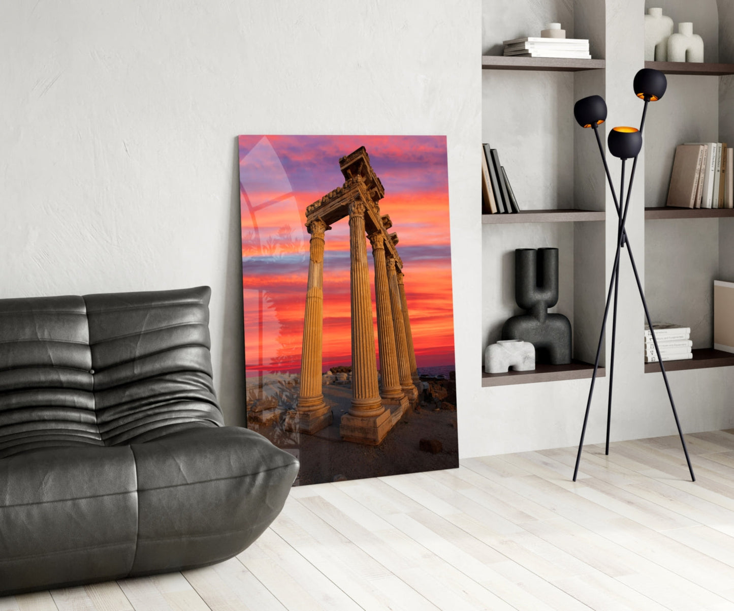 Temple of Apollo glass wall art displayed in modern living room with grey leather chair, black floor lamp, and white shelving unit.