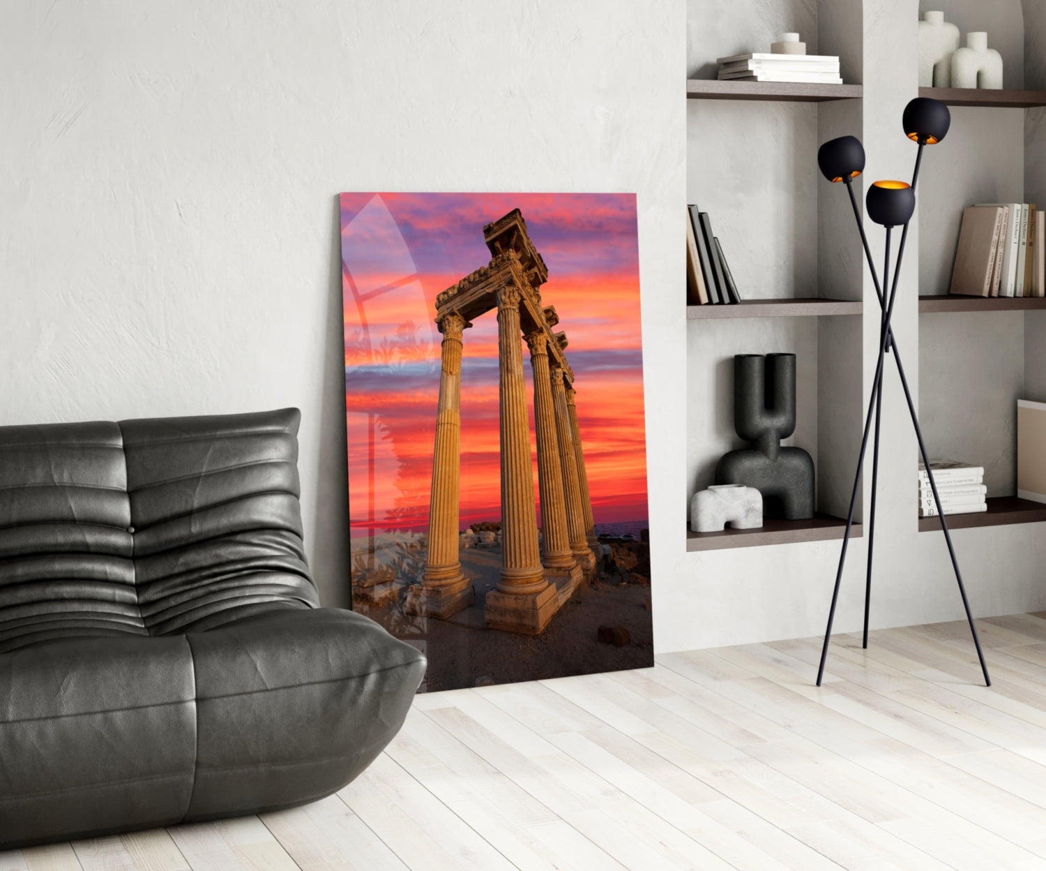Temple of Apollo glass wall art displayed in modern living room with grey leather chair, black floor lamp, and white shelving unit.