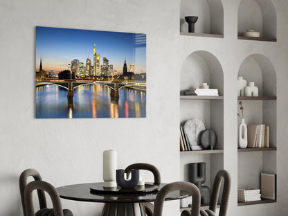 Frankfurt skyline at twilight with illuminated buildings and bridge reflections on glass canvas mounted above dining table.