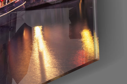Close-up angled view of glass wall art showing golden light reflections and warm amber tones through translucent material.