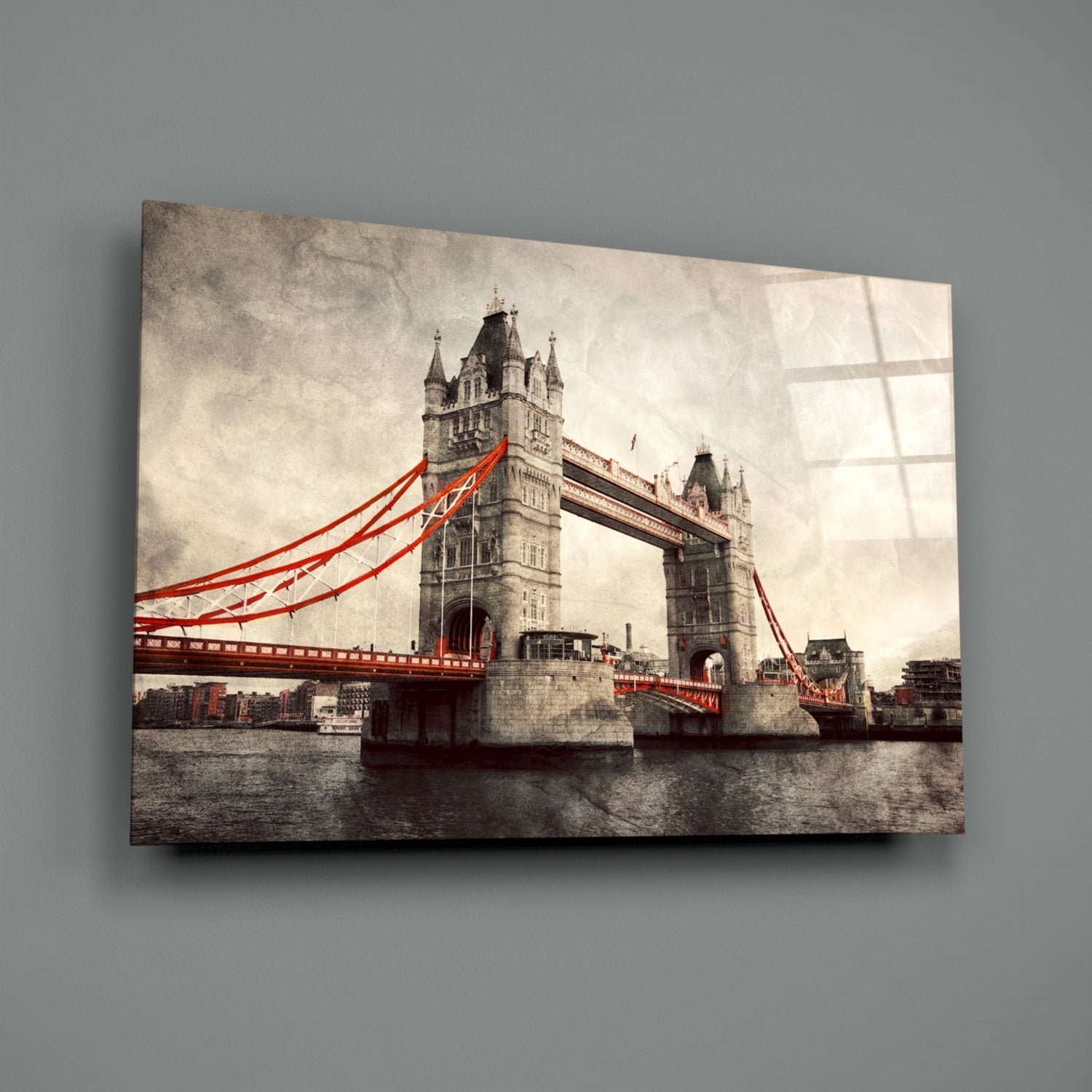 Tower Bridge London with bright red cables and towers displayed on a glass wall art panel against gray wall.