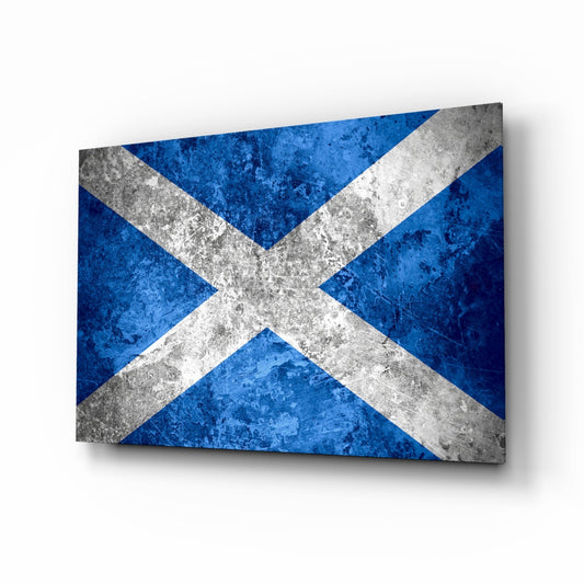 A rectangular glass panel displaying the Scottish saltire flag with a white X on deep blue background, rendered with weathered concrete texture and shadow effect.