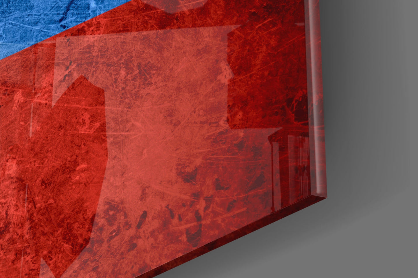 Close-up angled view of translucent red glass Russian flag art with blue stripe visible at top edge against gray background.