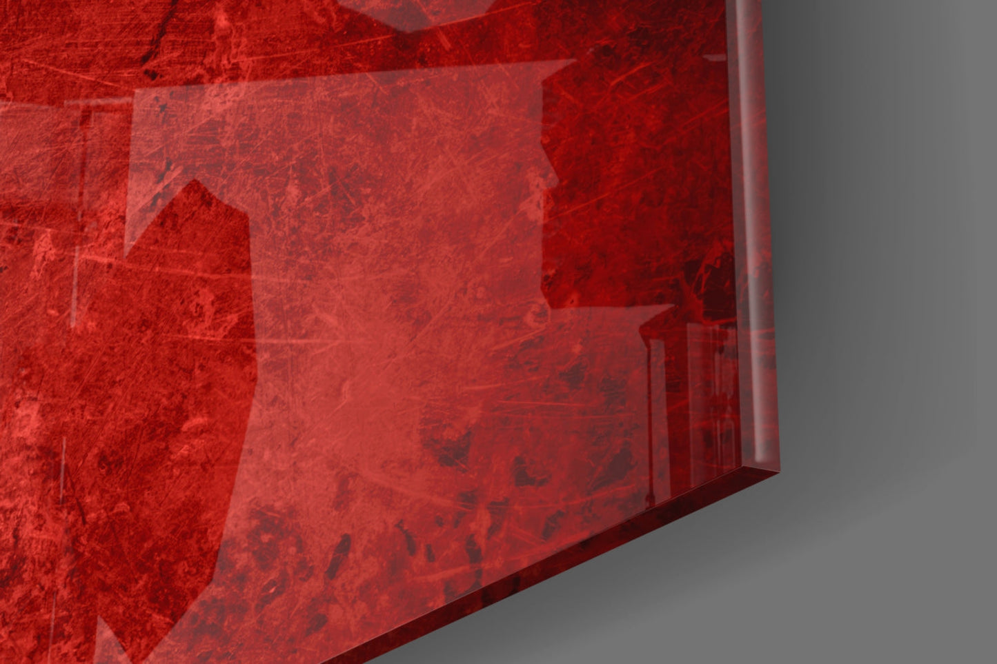 Red translucent glass wall art panel with textured surface and architectural imagery, photographed at angle against gray background.