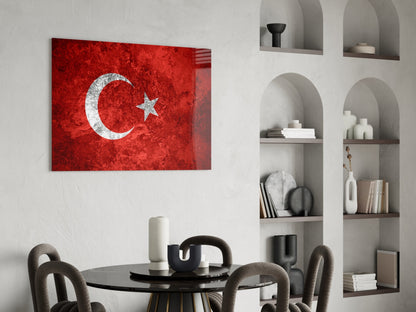 Turkish flag glass wall art with white crescent and star on red textured background, displayed above black dining table in modern interior.