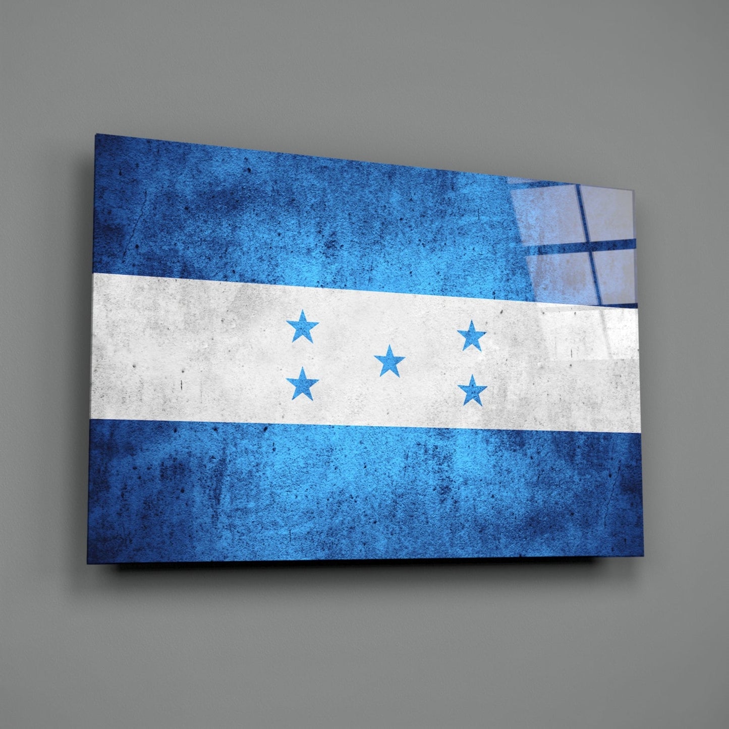 Angled view of Honduras flag glass wall art displaying three horizontal stripes in blue, white, and blue with five centered stars, mounted on gray wall.