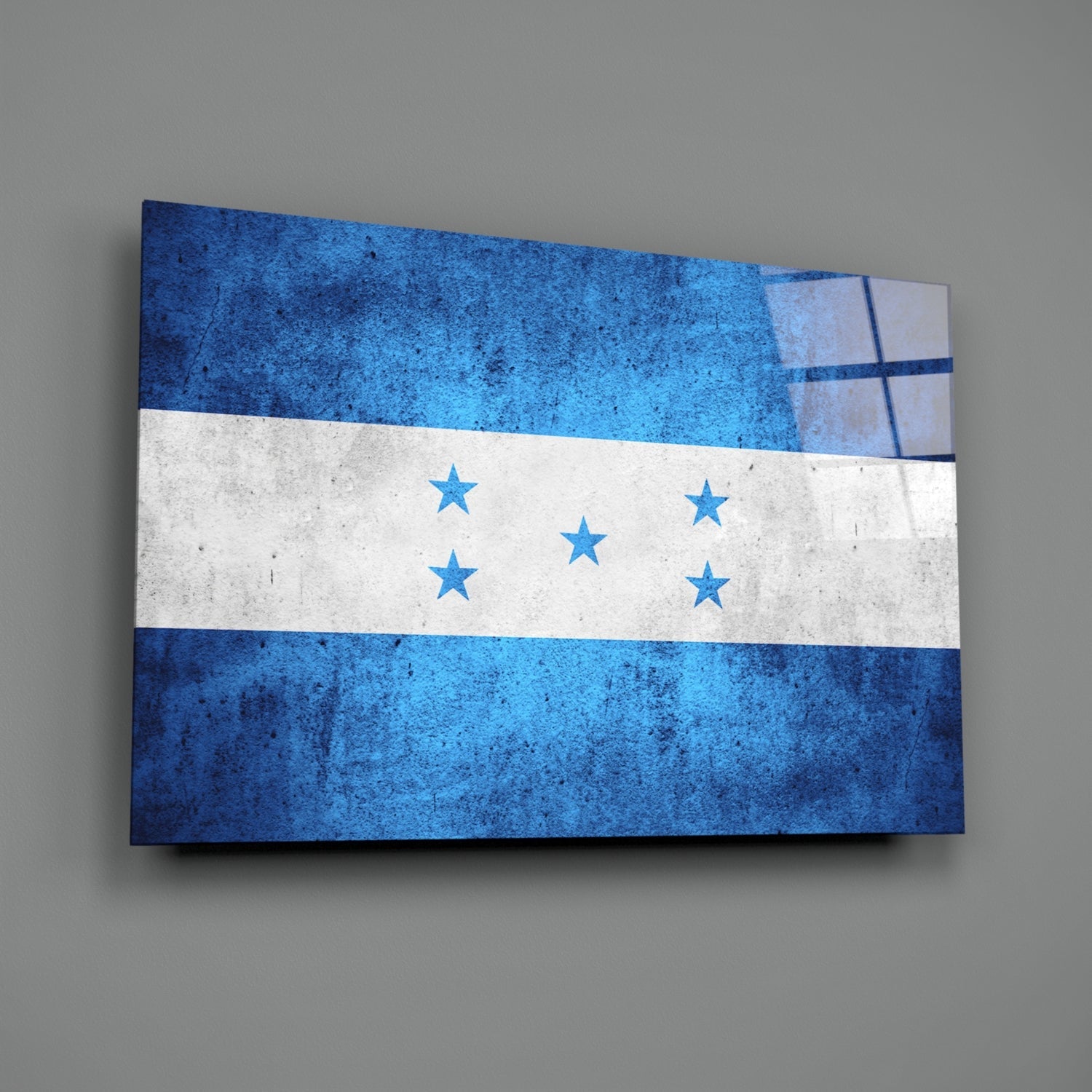 Angled view of Honduras flag glass wall art displaying three horizontal stripes in blue, white, and blue with five centered stars, mounted on gray wall.