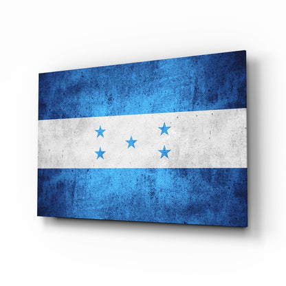 Angled view of Honduras flag glass wall art displaying three horizontal stripes in blue-white-blue with five blue stars, mounted at perspective angle.