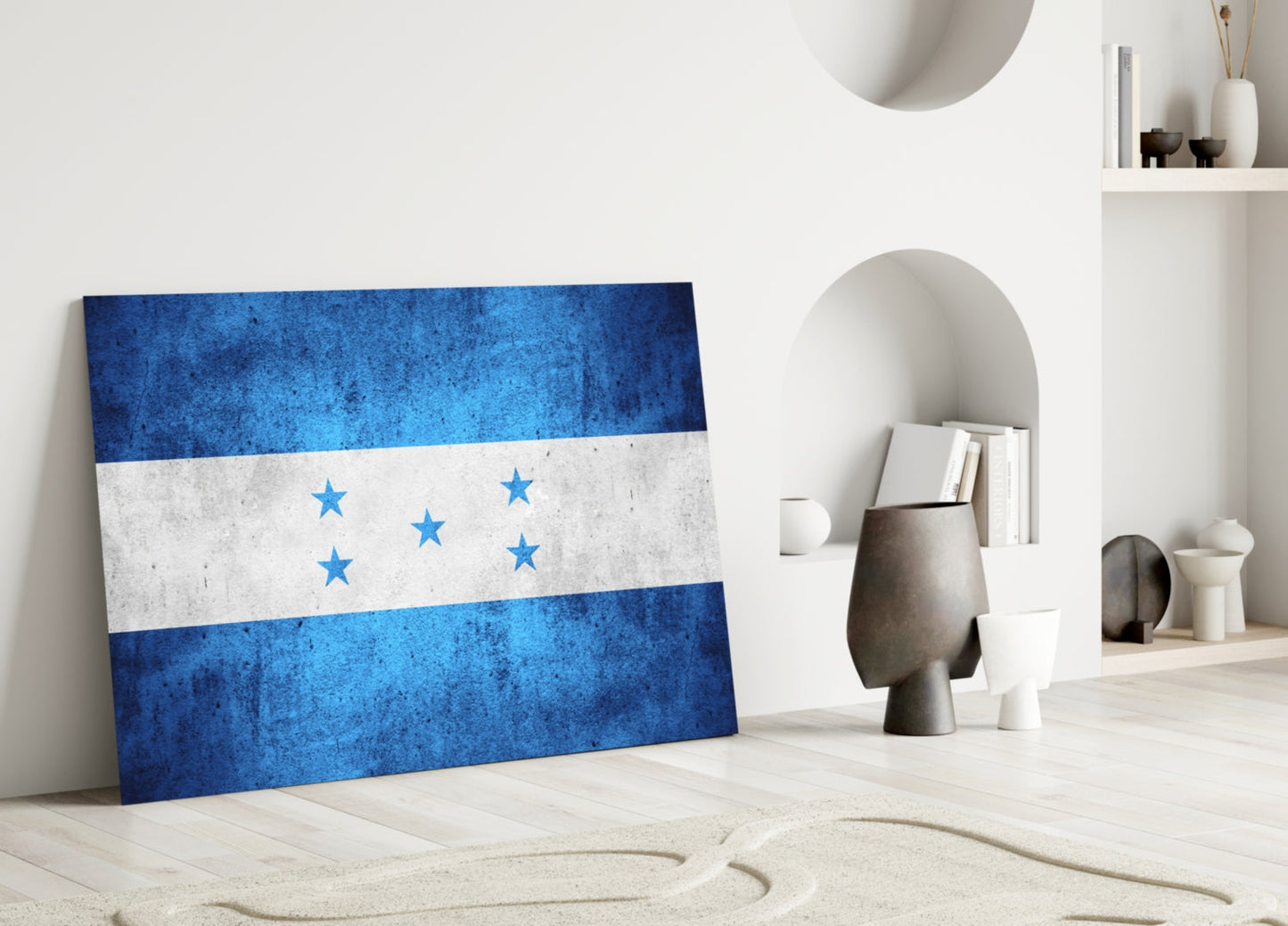 Honduras flag glass wall art leaning against white wall in minimalist interior setting with decorative objects.