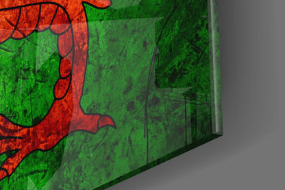 Close-up angled view of Welsh flag glass art showing red dragon on bright green background with visible glass edge and shadow.
