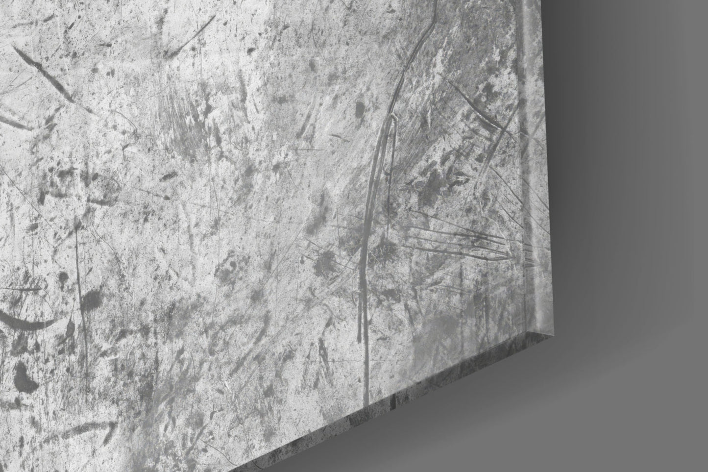 Close-up of textured concrete surface with scratches and dark marks, showing edge detail of glass wall art.