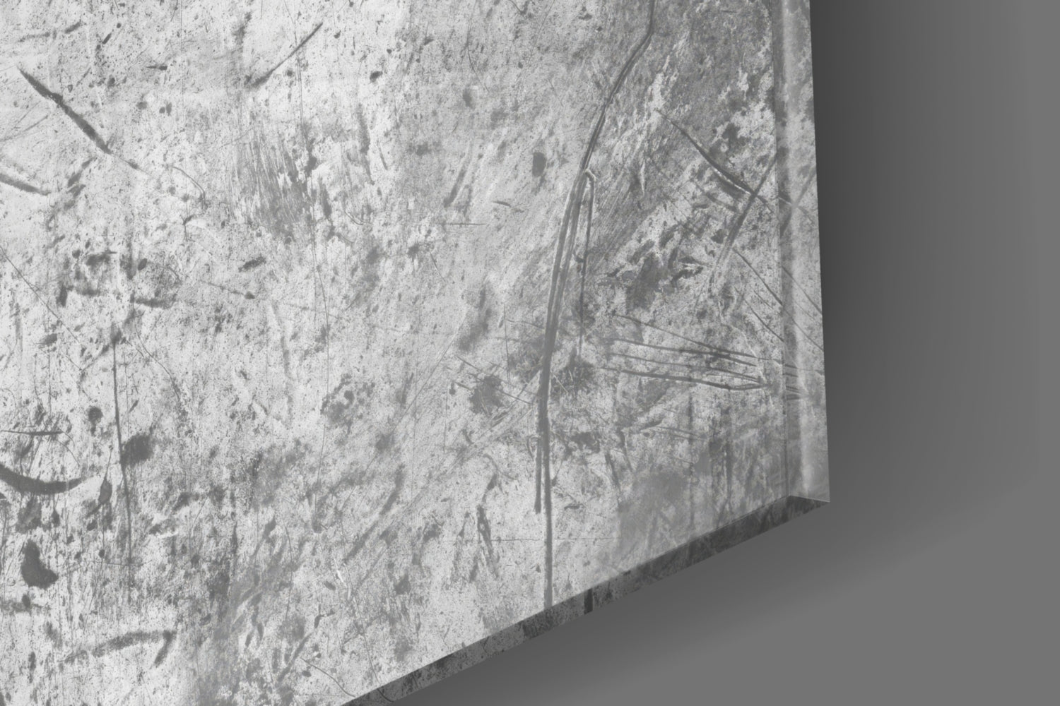 Close-up of textured concrete surface with scratches and dark marks, showing edge detail of glass wall art.