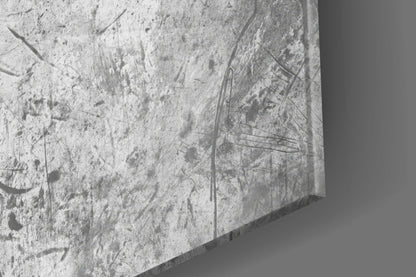 Close-up of textured concrete surface with scratches and dark marks, showing edge detail of glass wall art.