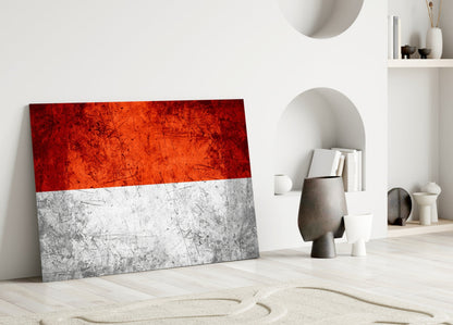 Indonesian flag glass wall art leaning against white wall in minimalist interior setting.